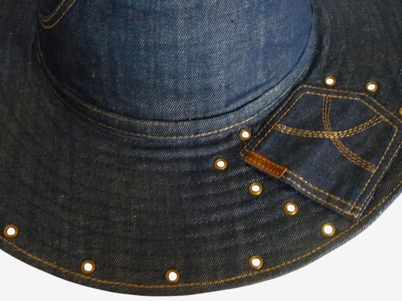Close-up of pockets, eyelets, and contrast stitching on dark blue denim wide brim hat