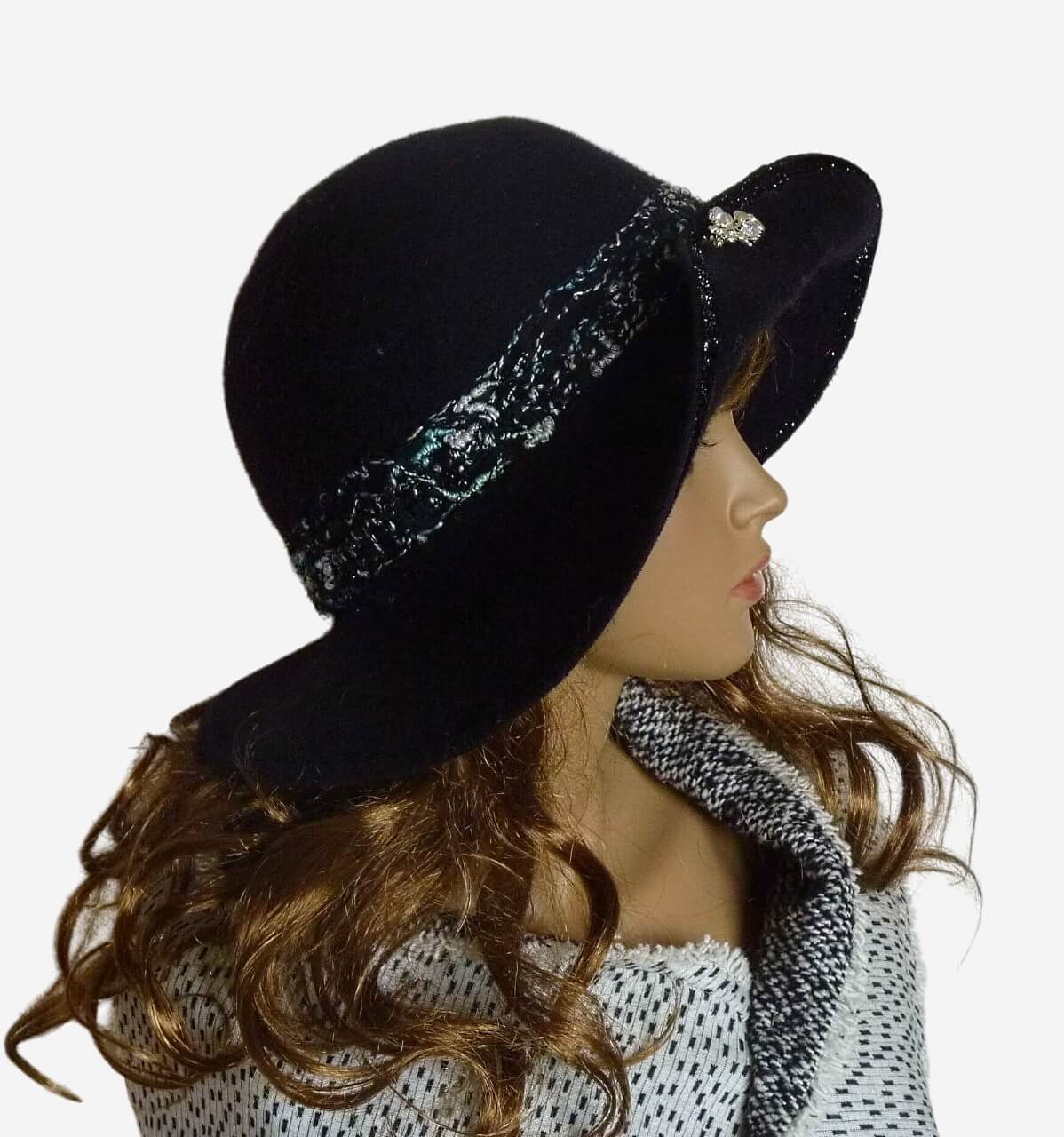 Black felted wool hat with medium brim and decorative brooch displayed on mannequin