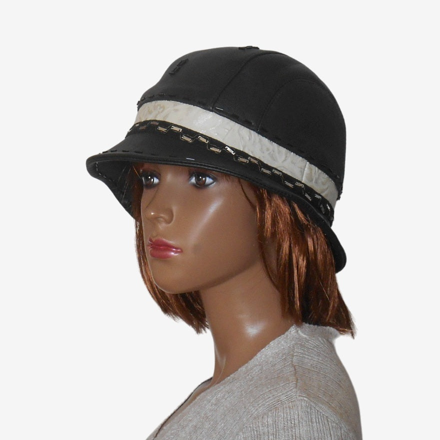 Three-quarter view of a women’s black leather hat with narrow brim and decorative braid