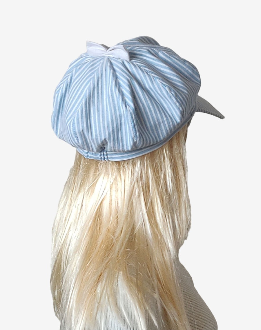Back view of women’s blue and white striped newsboy cap with white bow