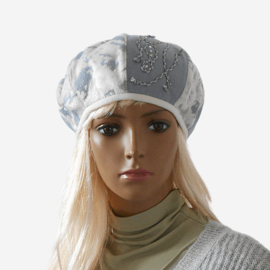 A women's blue and white warm beret with short pile faux fur and wool fabric, featuring a decorative braid on one side, displayed on a mannequin head.