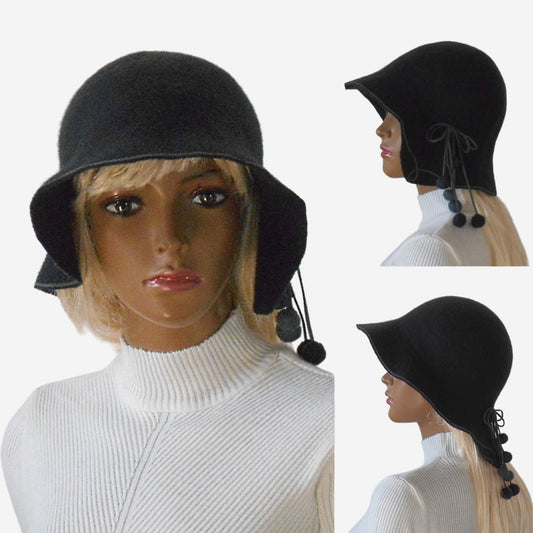 A dark gray wool hat with pompoms, displayed on a mannequin head, showing the front and side views