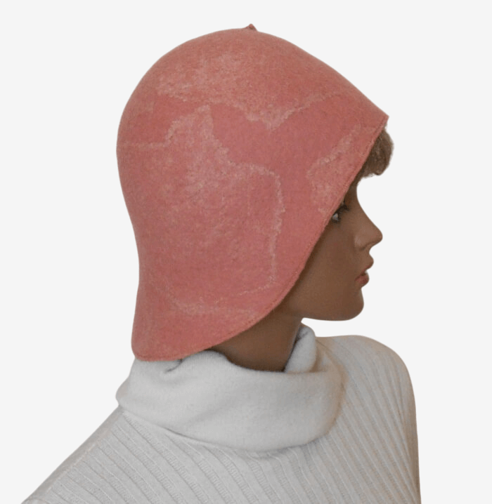 Side view of handmade pale pink felted hat with asymmetrical brim and decorative brooch