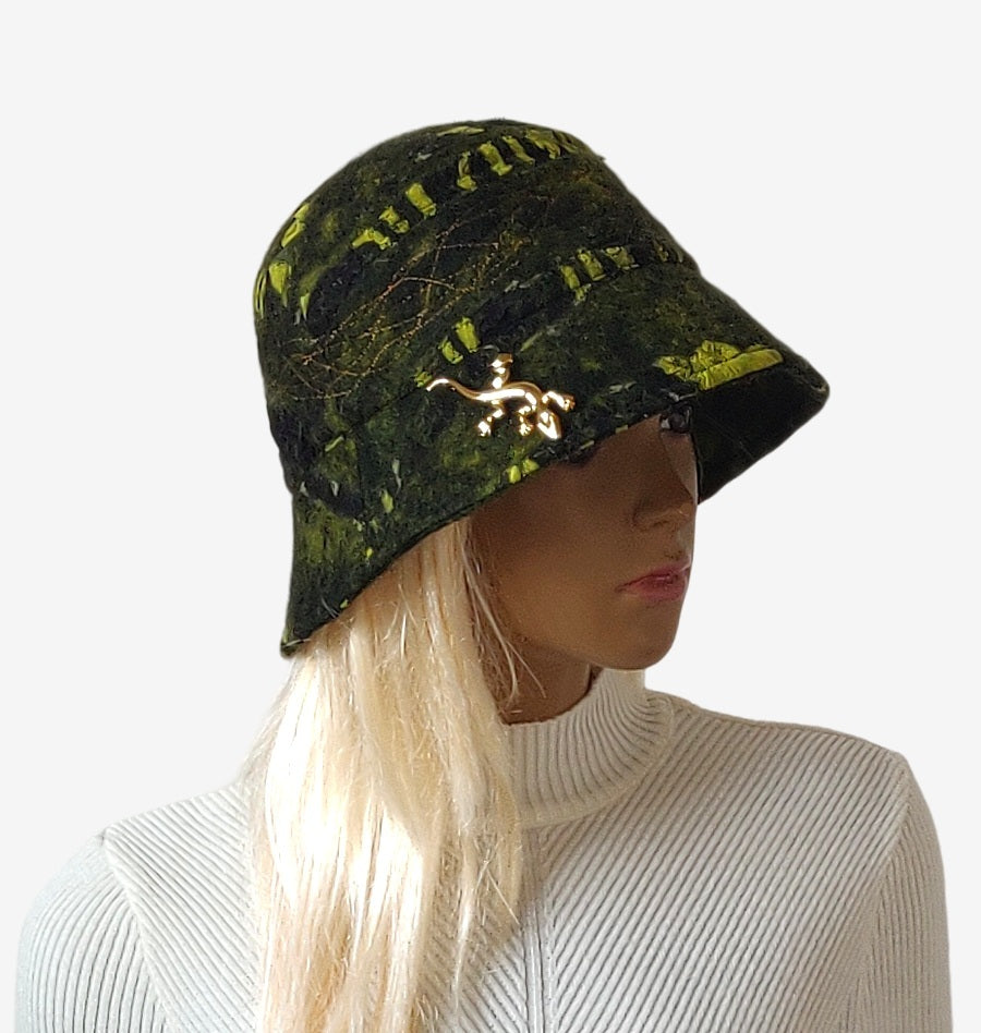 Three-quarter view of warm green felted merino wool bucket hat with removable brooch, showing shape and color combination