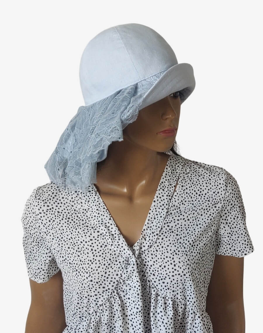 Three-quarter view of a romantic light blue linen summer hat with asymmetrical brim and draped lace