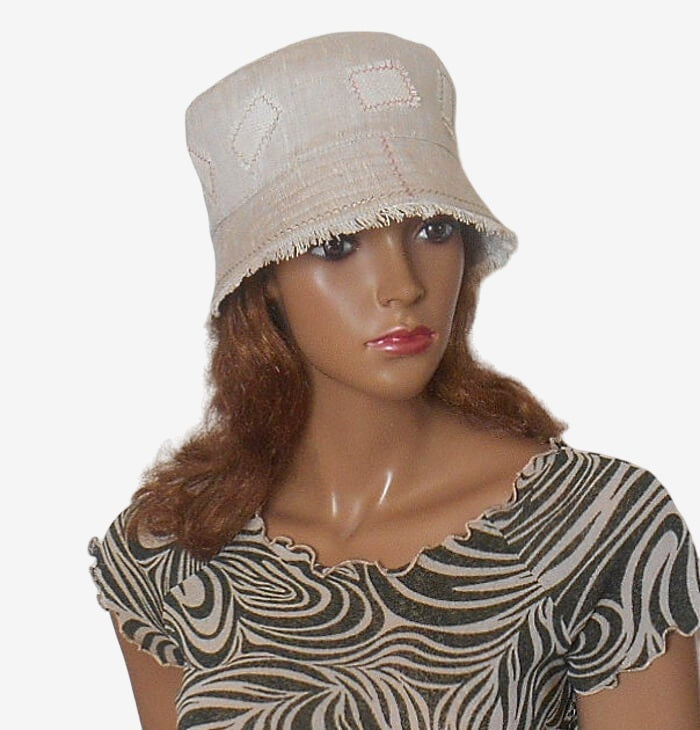 Three-quarter view of beige linen bucket hat, eco-friendly summer hat with fringe, casual and stylish