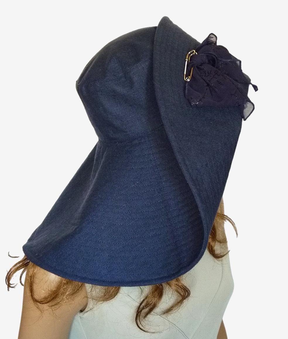 Side view of navy wide-brim linen hat with decorative bow and pin