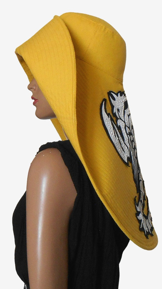 Side view of yellow asymmetrical wide brim linen hat, showing Dragon appliqué detail